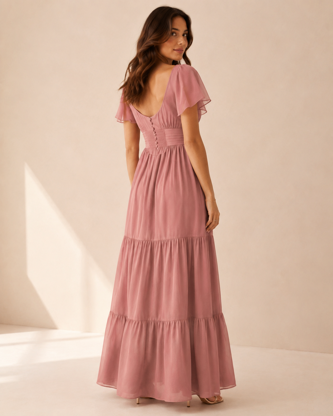 Model wearing the Aurora Bloom Maxi Dress from a back three-quarter view with bow detail